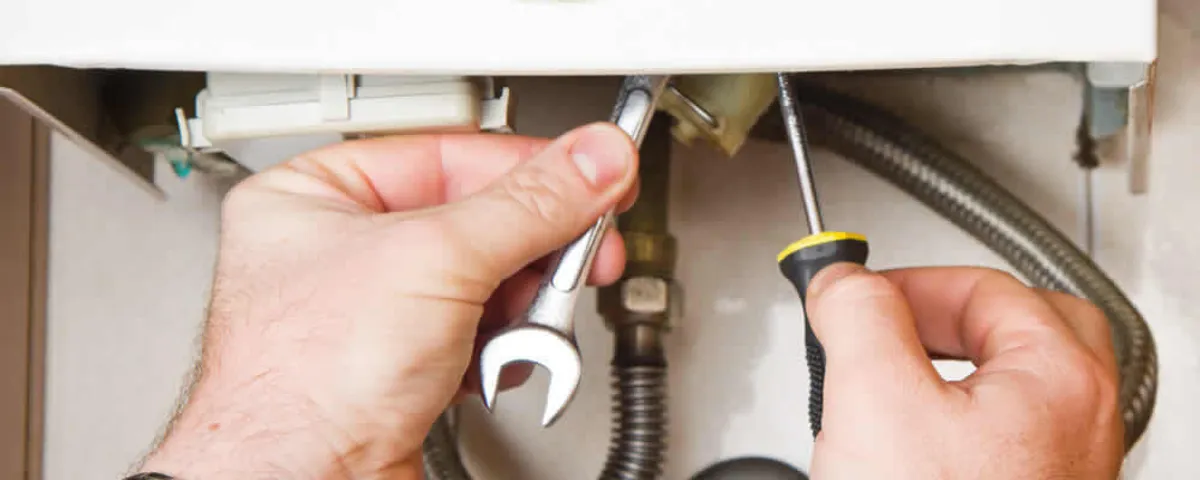 Boiler repair technician tightening pipe fittings and connections in Chandler, AZ