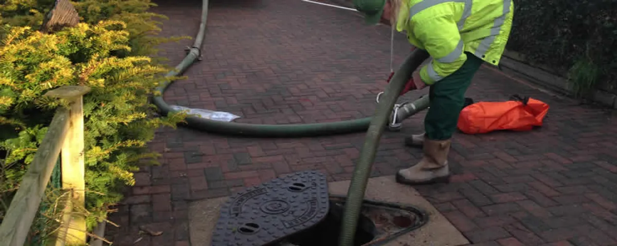 Septic tank cleaning technician servicing a septic tank with a vacuum hose in Chandler, AZ